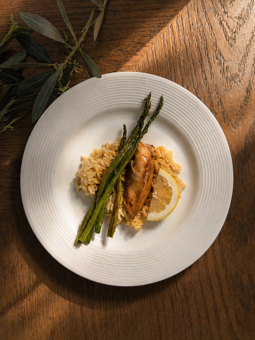 Plated lemon butter chicken with parmesan orzo and roasted asparagus